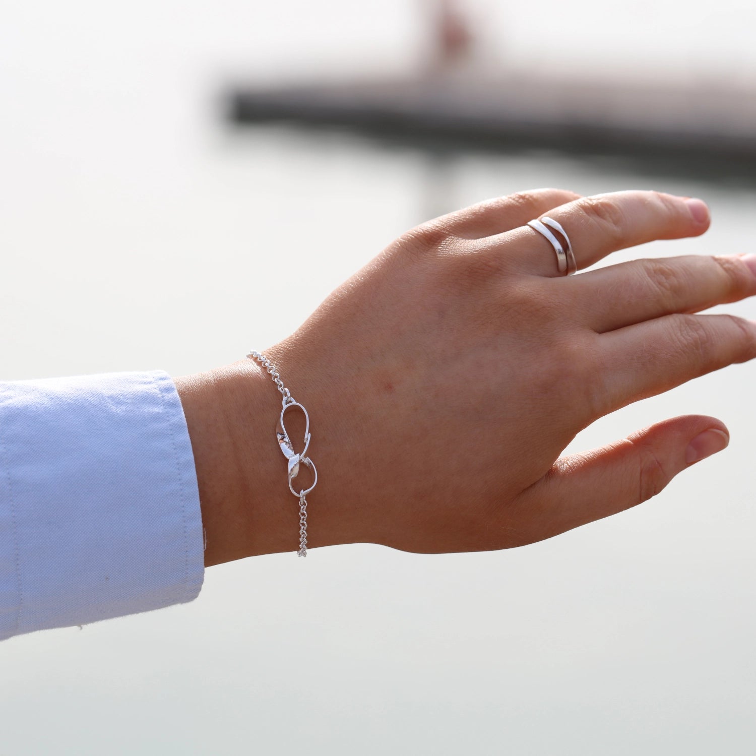 Wrist shot of a silver STORMSKÄRS MAJA bracelet with a double curved loop charm on the chain