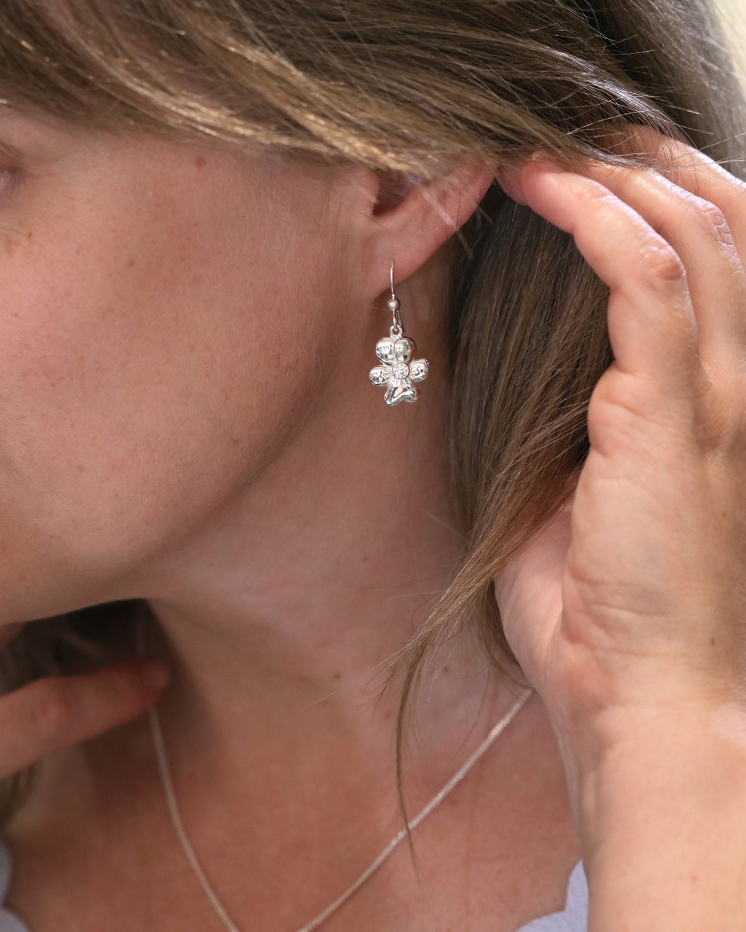Silver flower drop earring on a hook with a central cubic zirconia.
