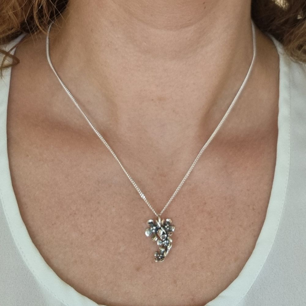 Silver halsband med blomsterhänge visas på modellens hals
