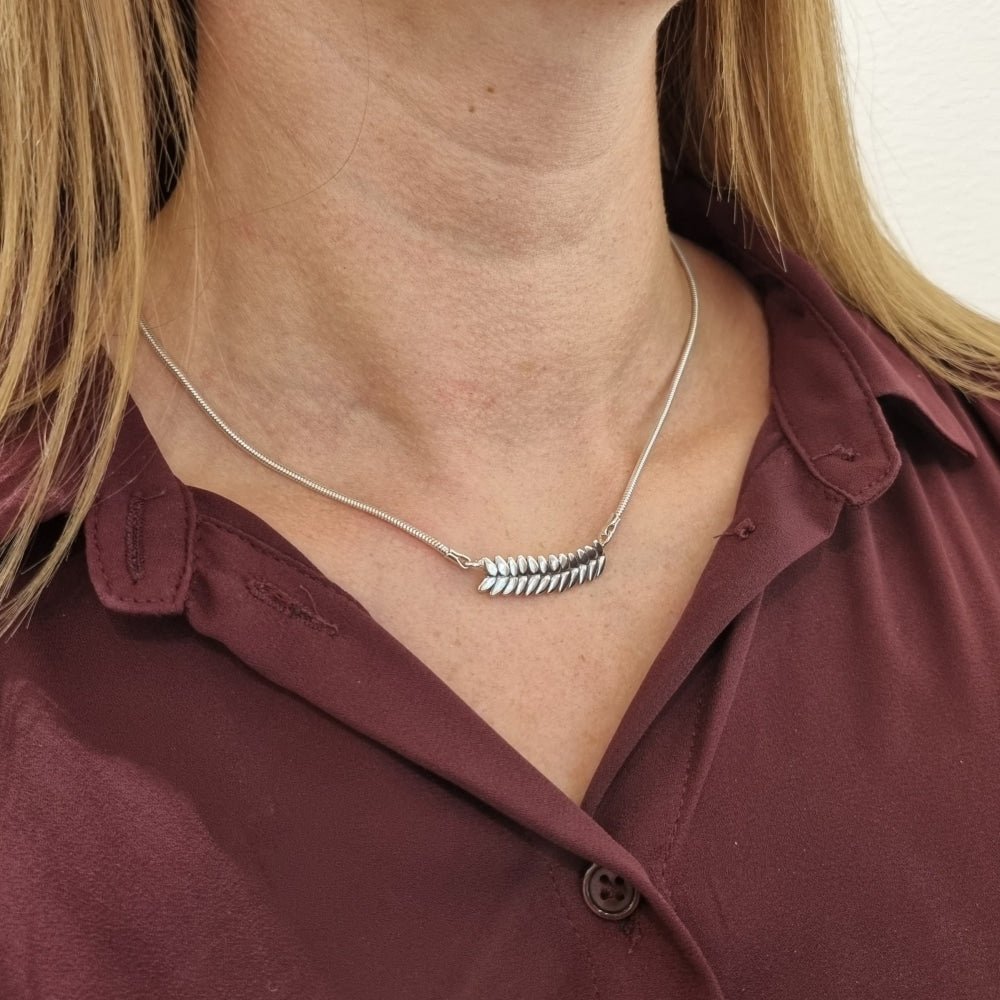 Kvinna bär RÅG halsband med bladformad silverlänk över halsen