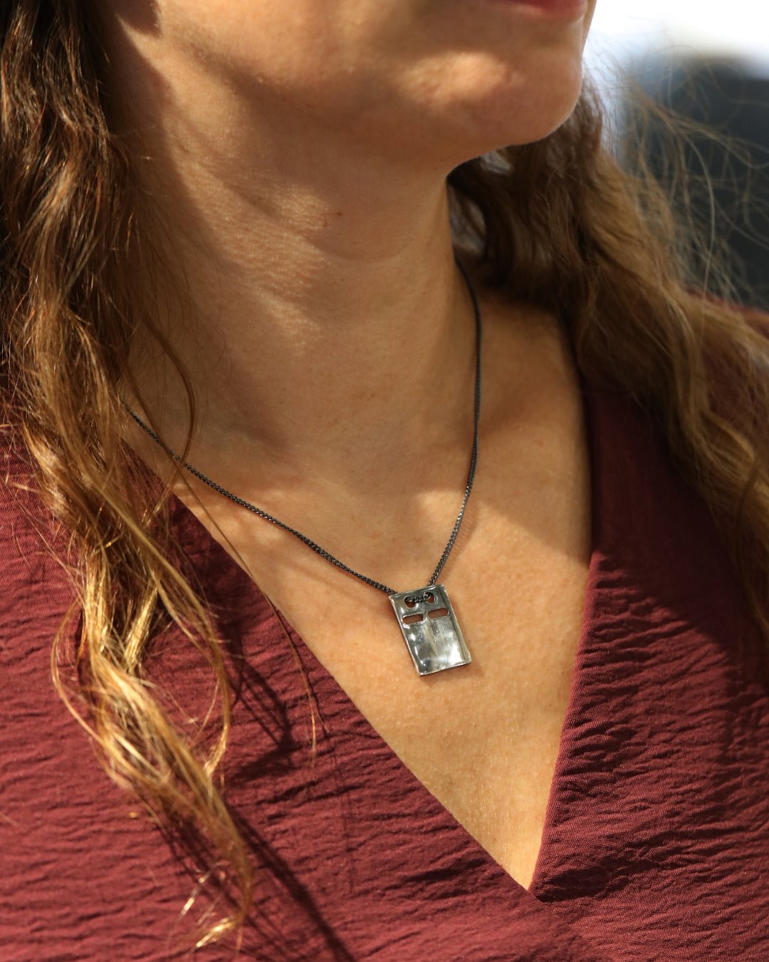 Model wearing silver ID bricka necklace with an irregular rectangular pendant at the collarbone