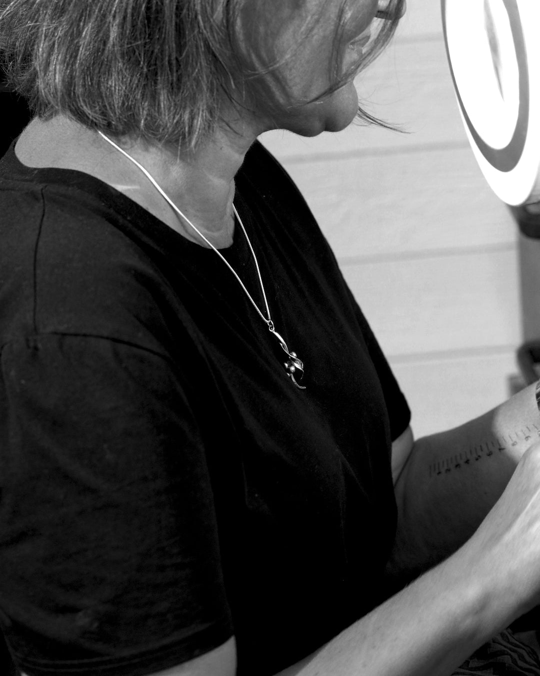 HAVTORN halsband in 925 sterling silver worn on a black shirt with the curved pendant visible