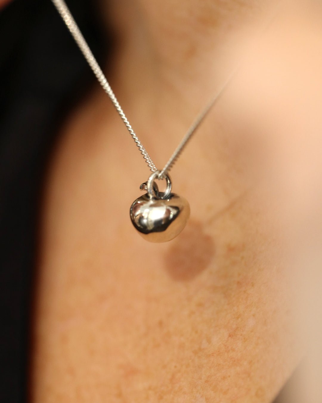 LJUVLIG halsband i sterlingsilver med blankt äpplehänge och blad mot hudfärgad bakgrund