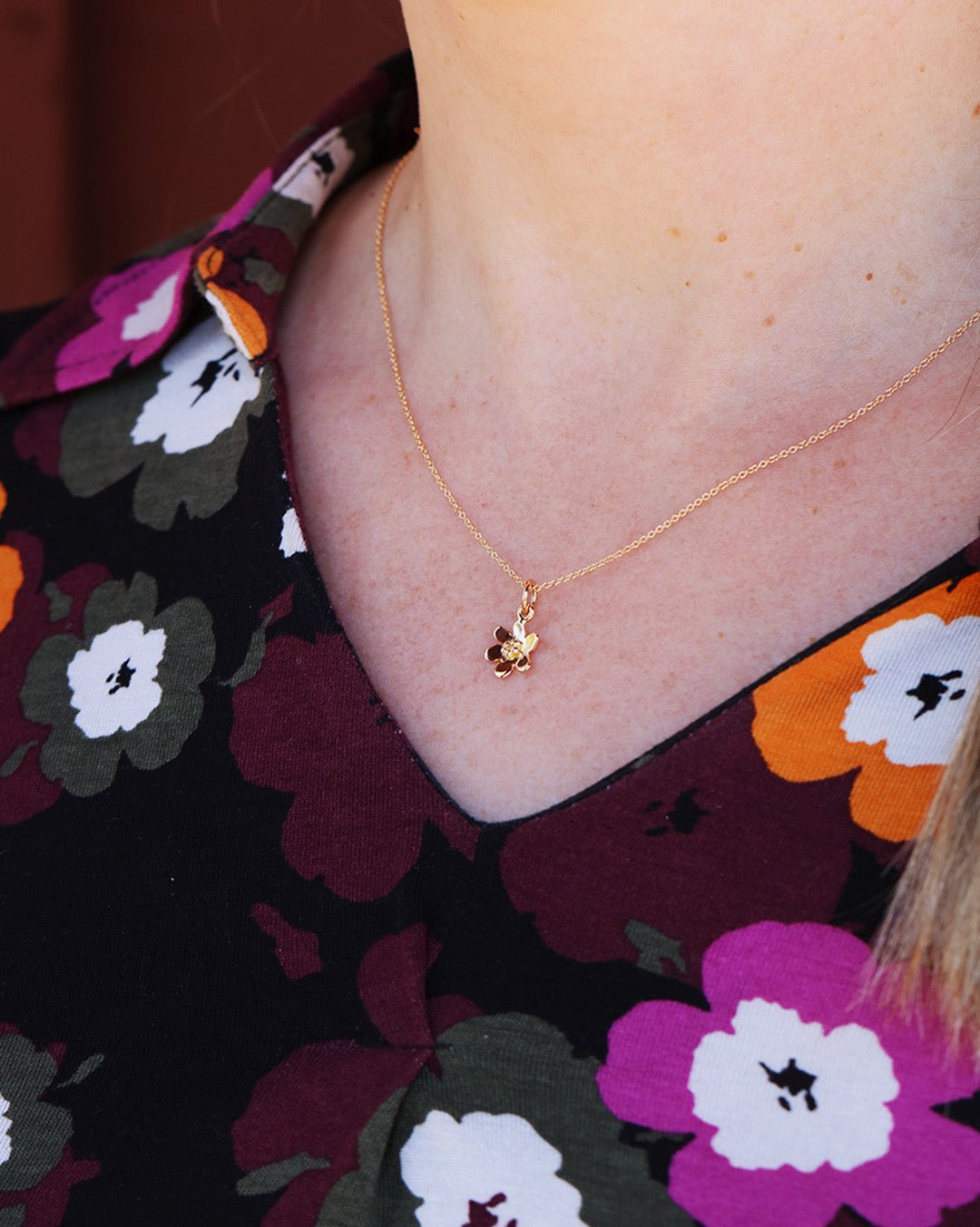 Kvinna bär Blåsippa XS halsband i 18K guld runt halsen