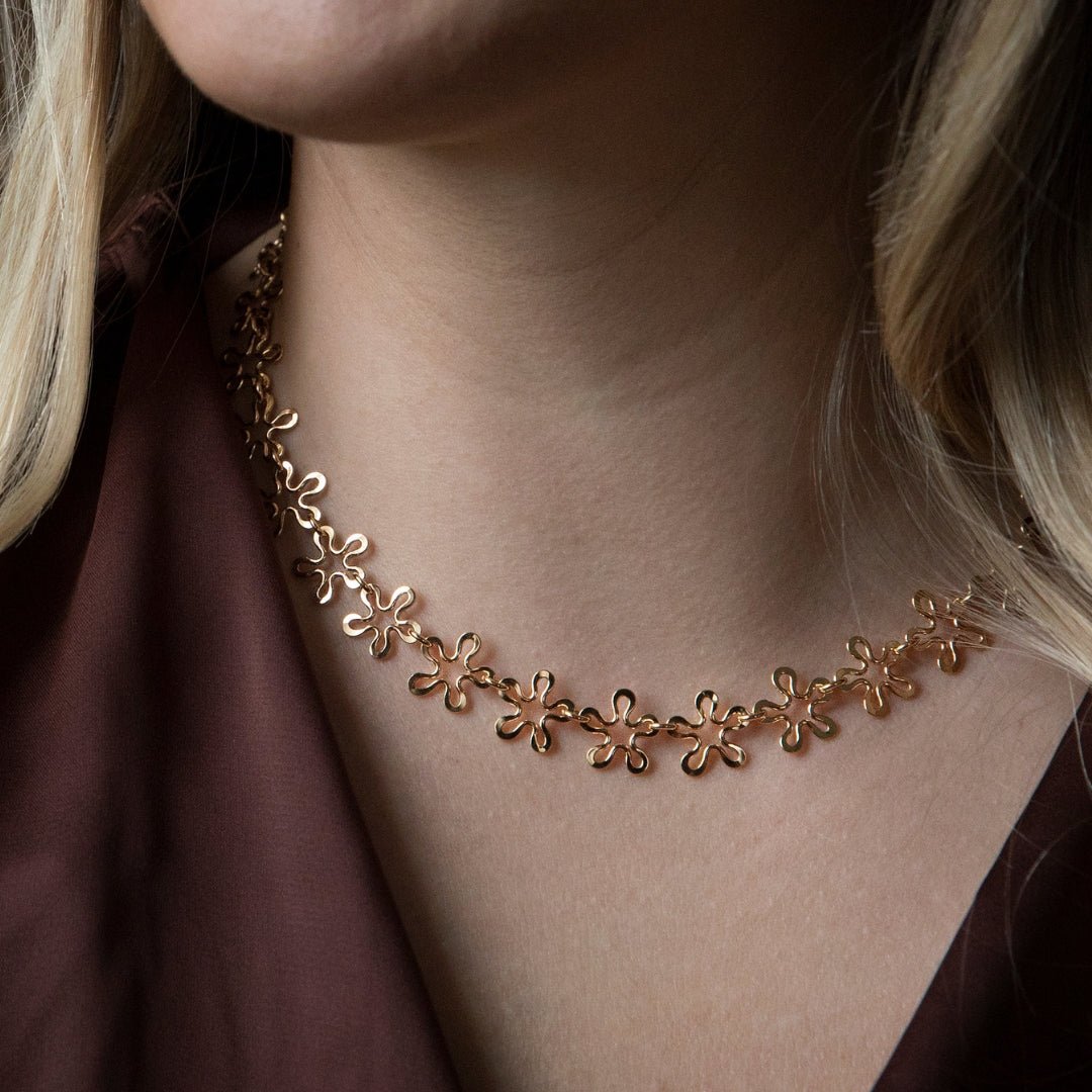 Gold BLOMMAN flower necklace with connected four petal blooms worn on the neck