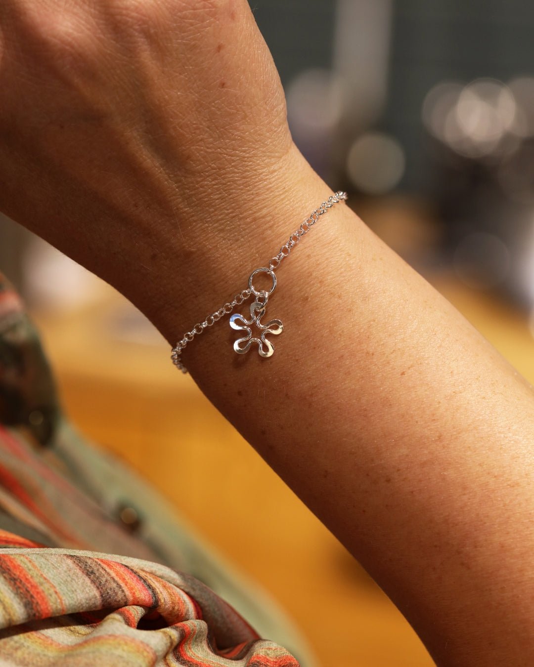 Close up of BLOMMAN XS armband with a flower charm on a delicate silver chain worn on a wrist