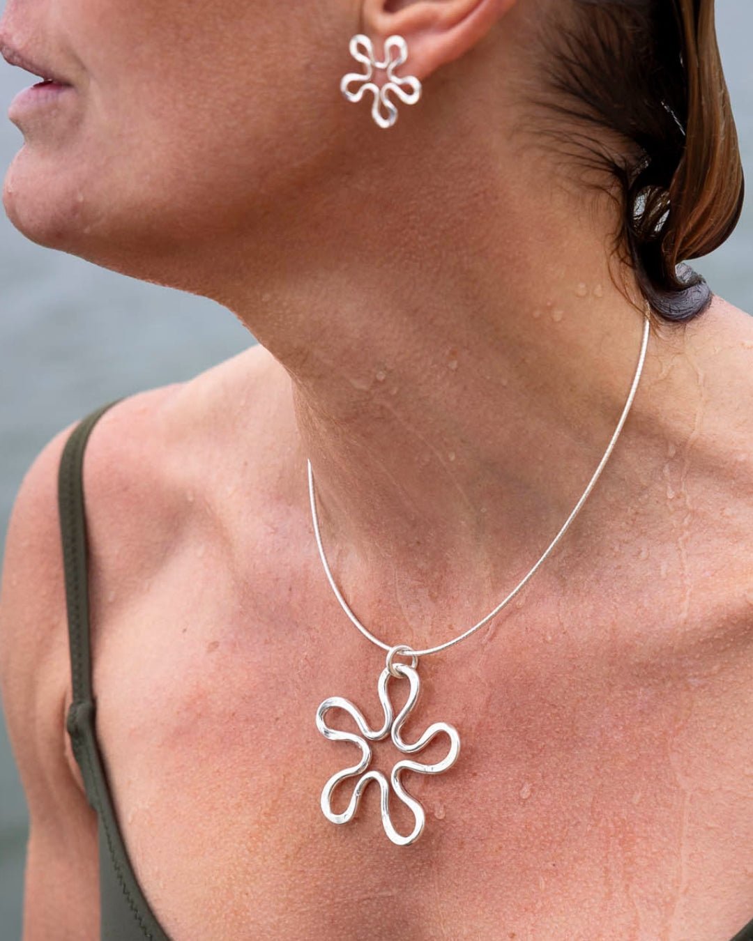 BLOMMAN XL halsband i silver med 60 mm blomformigt hänge bärs av en kvinna