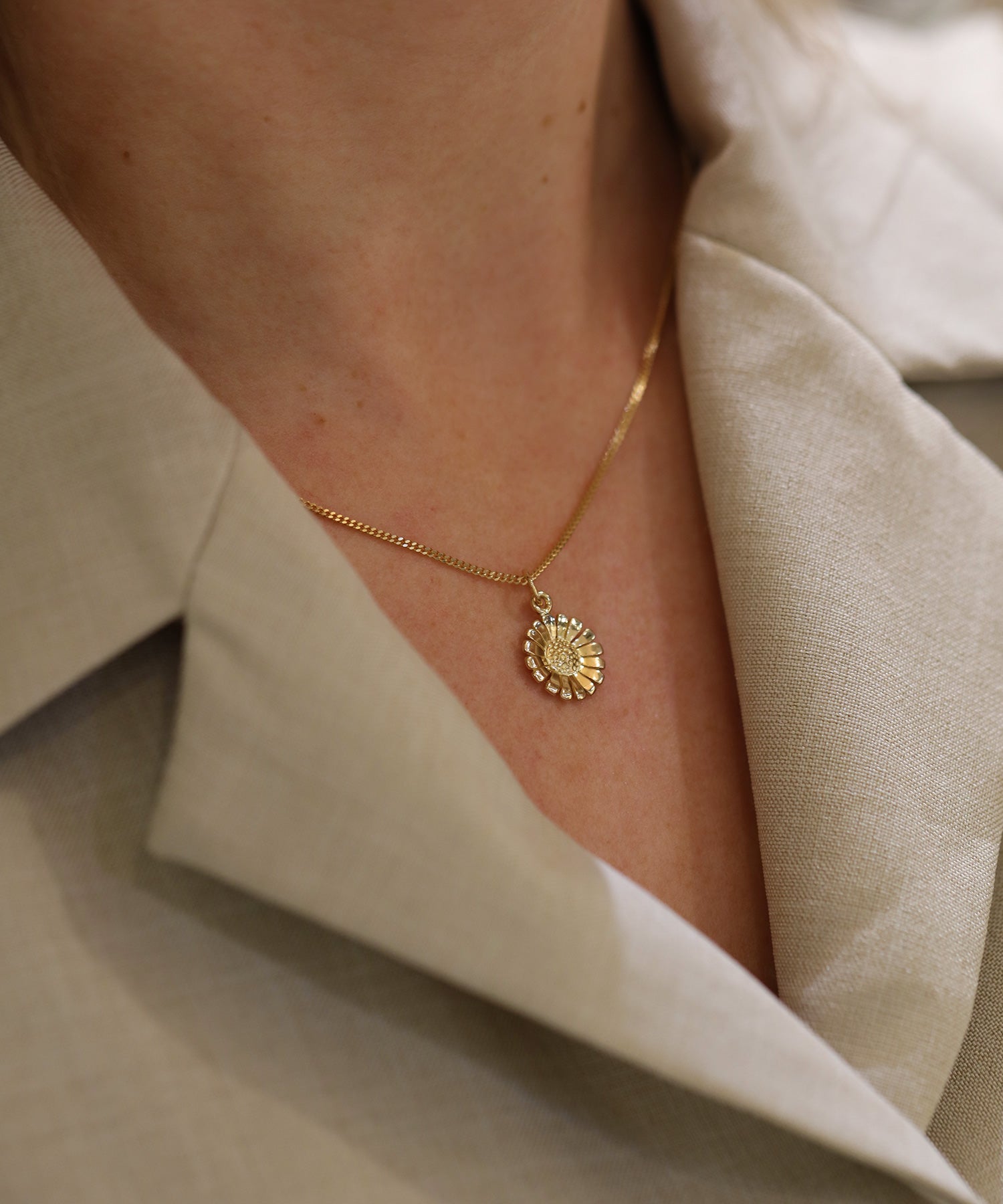Guld Daisy halsband med blomsterhänge runt modellens hals