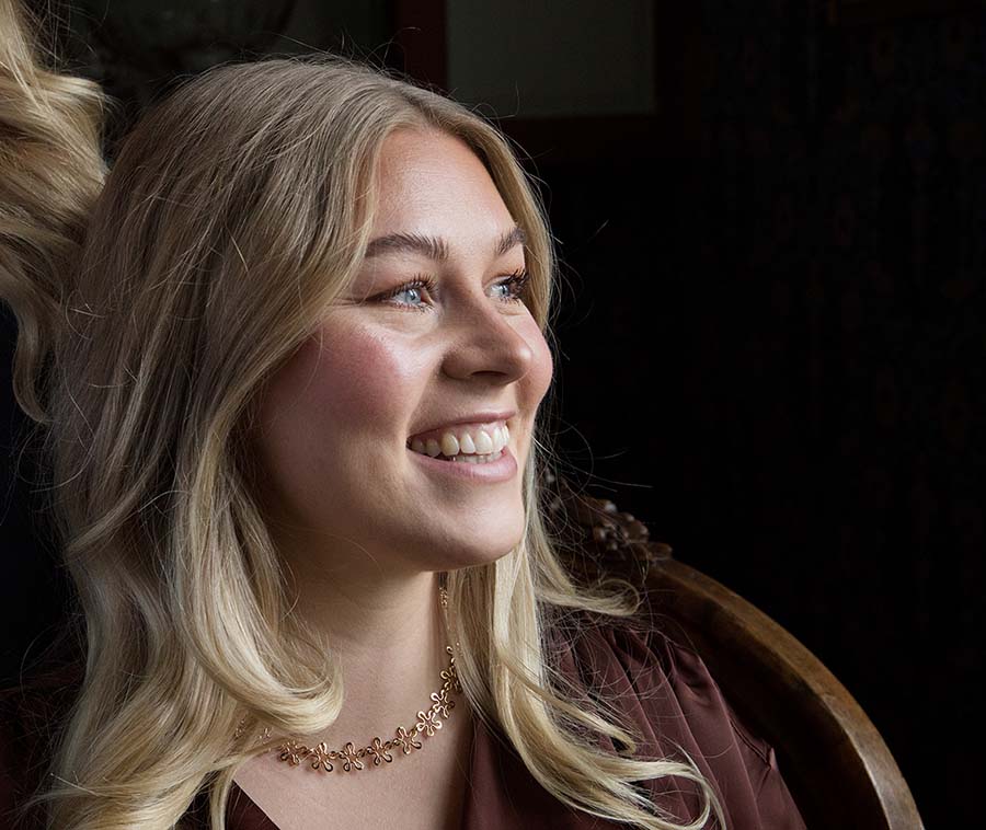 Smiling woman wearing BLOMMAN 18K collier exklusiv rose gold floral necklace.