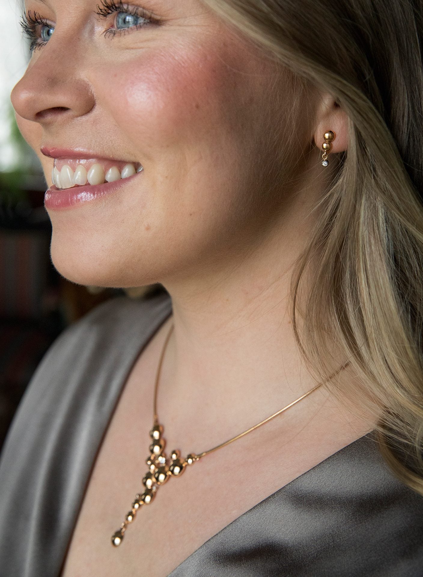 Kvinna bär CELEBRATE Collier 18K guld med bubbelkluster och diamantpendel längs halsen