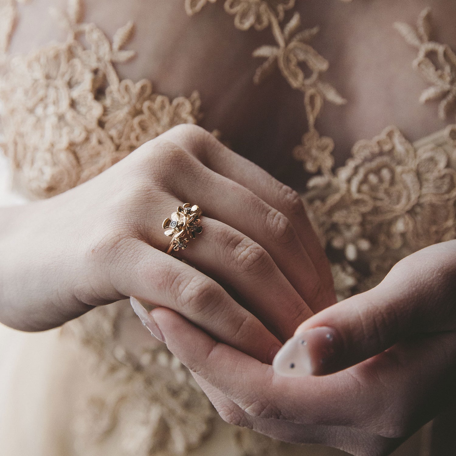 Närbild av äppelblom ring i 18K guld med diamanter bärs på fingret.