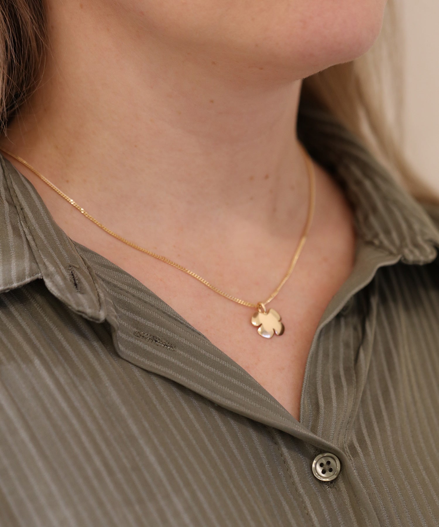 KLÖVER 18K halsband med ett litet klöverhänge i guld på tunn kedja runt halsen