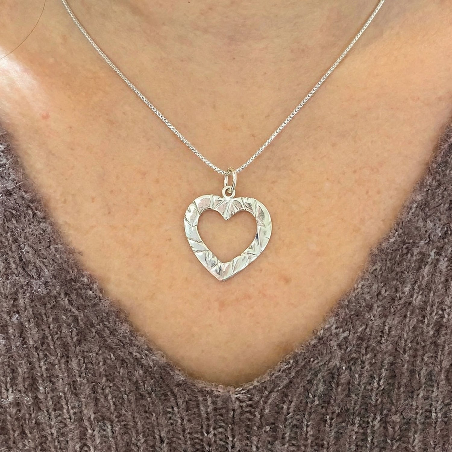 Kvinna bär silver MULTIHJÄRTA halsband med öppen hjärtberlock runt halsen