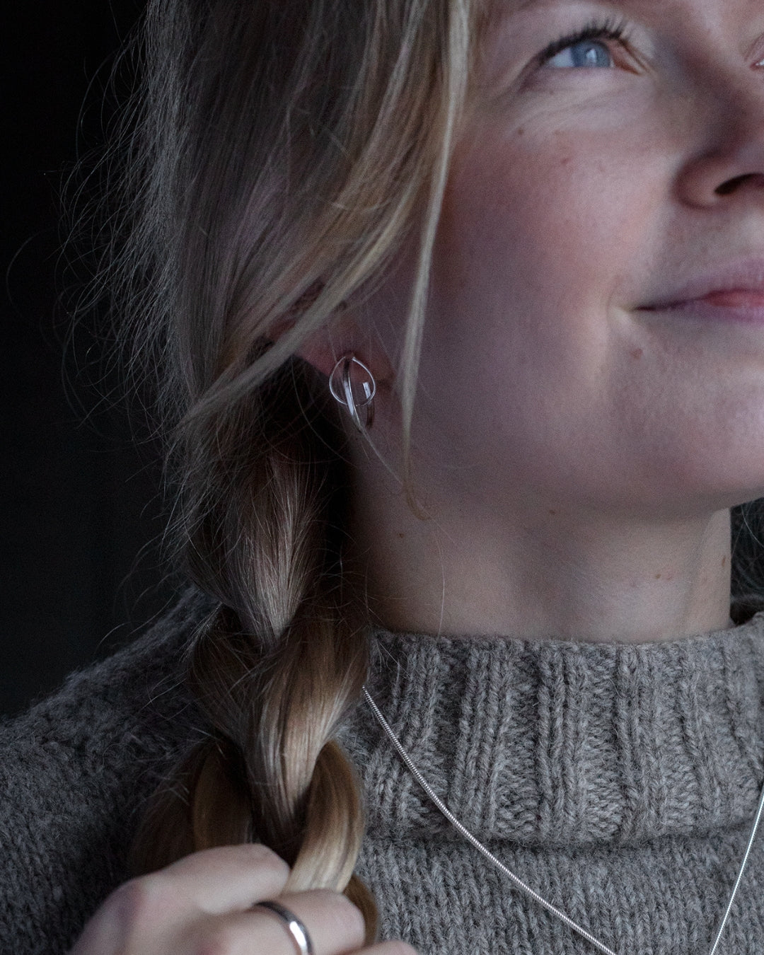 Kvinna bär STORMSKÄRS MAJA örhängen på stift i silver med öppen oval design