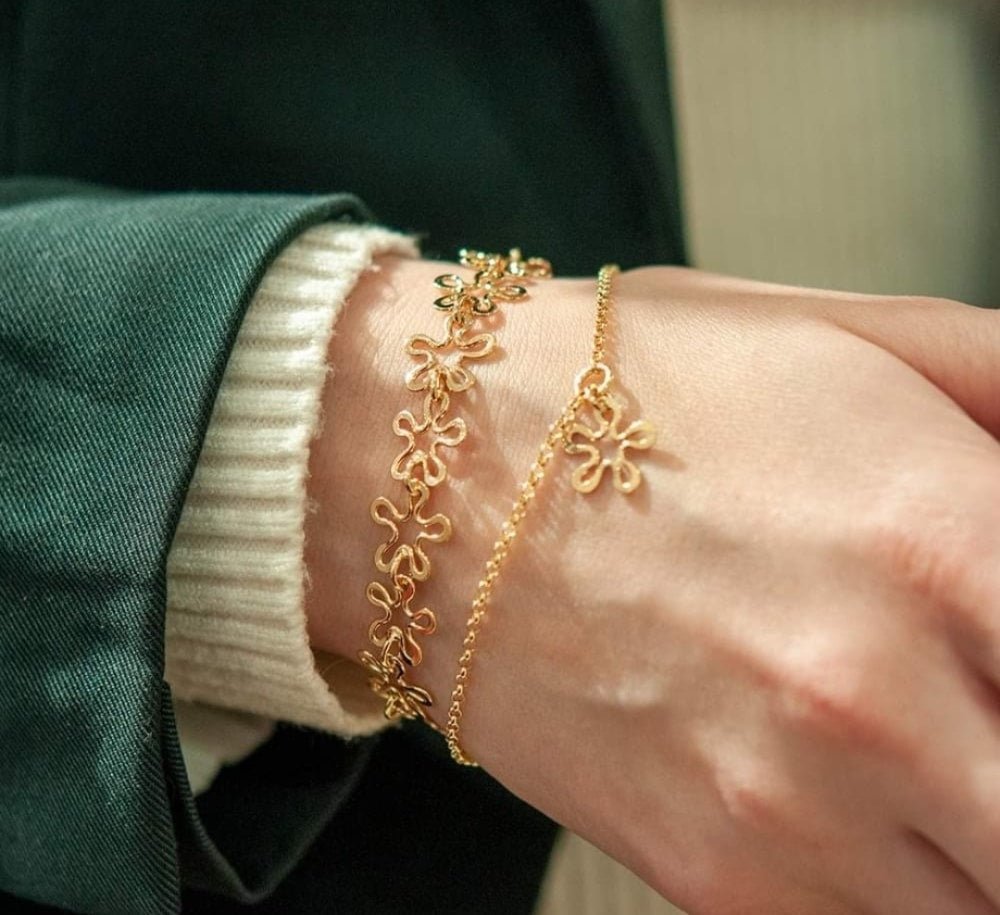 Handled med tre guld BLOMMAN smycken, två blomformade berlocker och en tunn kedja