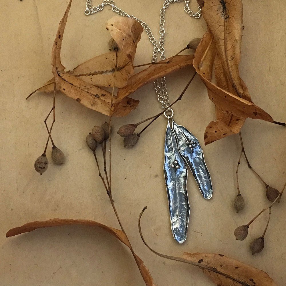 Close-up of Tilia necklace with two patinated leaf pendants and small beads