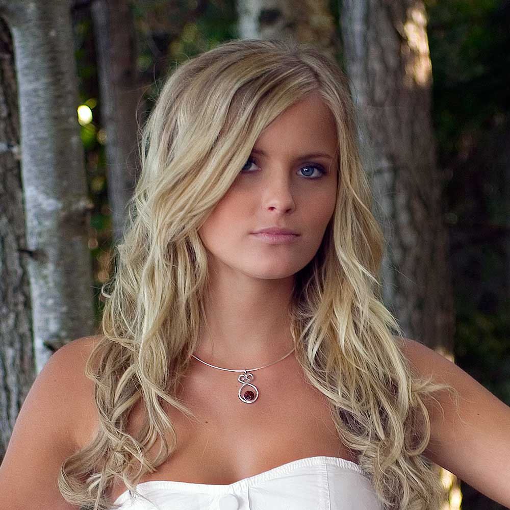 Modell bär ÅLANDSHJÄRTA L halsband i silver med röd granit mot naturbakgrund