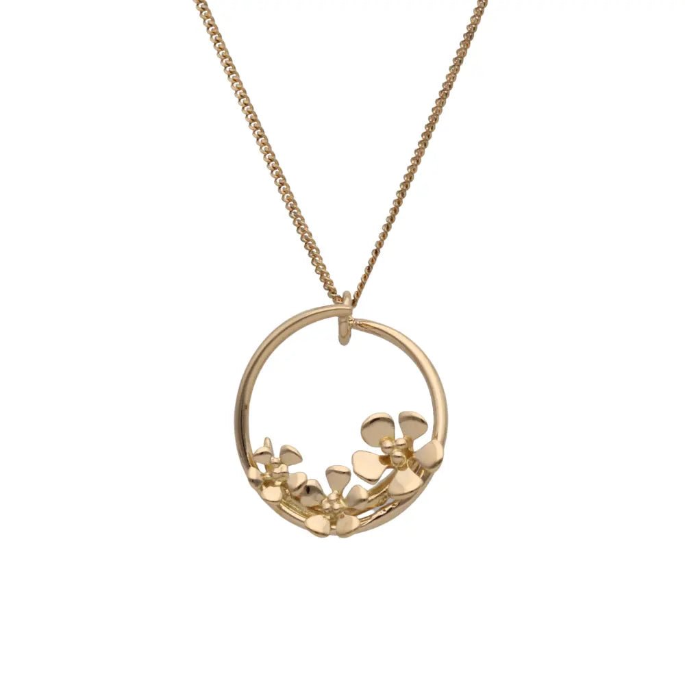Gold circular pendant with tiny flower motifs along the lower arc on a chain
