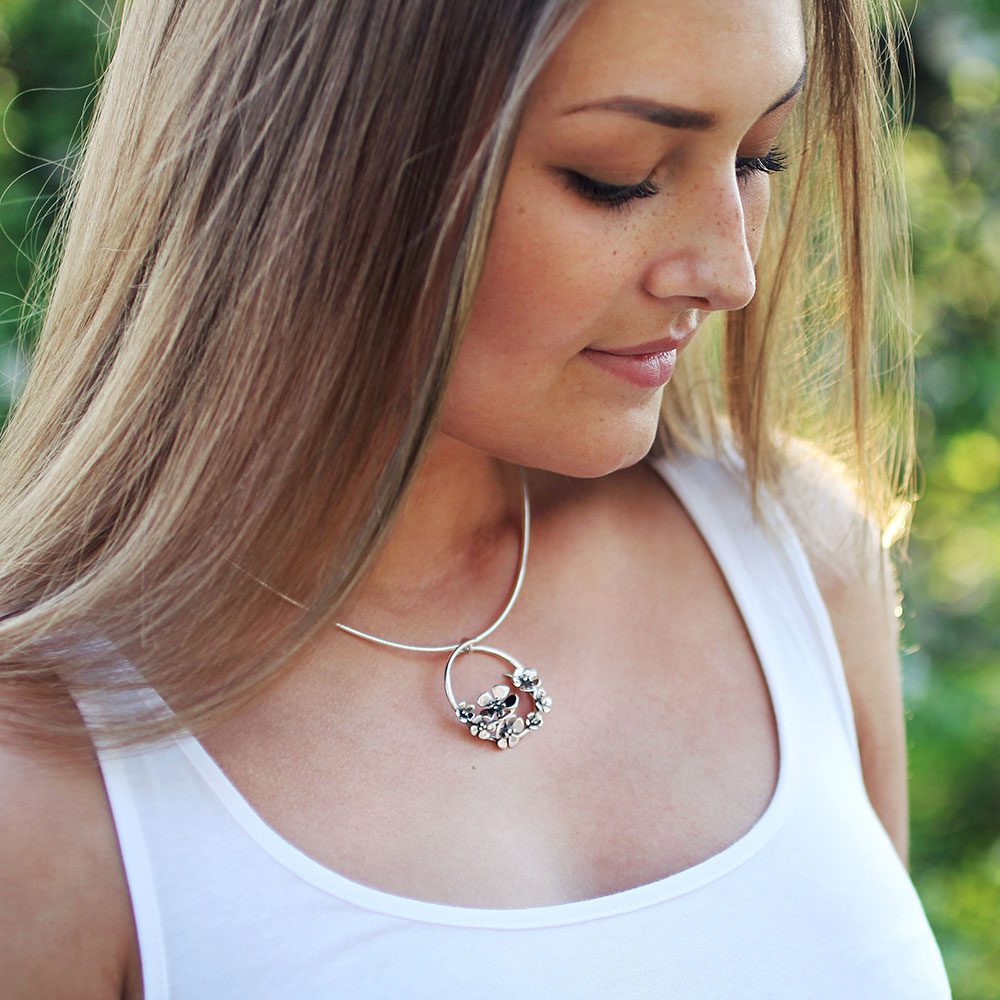 Modell bär ÄPPELBLOM L halsband i silver med blomcirkelhänge runt halsen