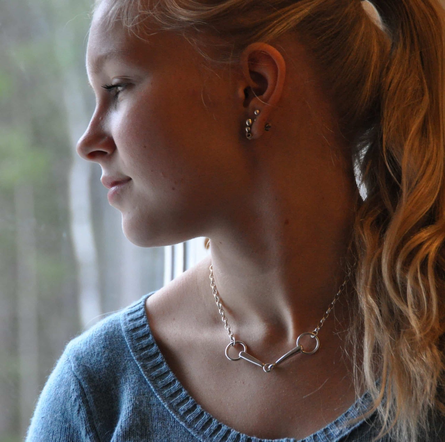 Side profile of a woman wearing BETSEL silver chain necklace and multiple small earrings