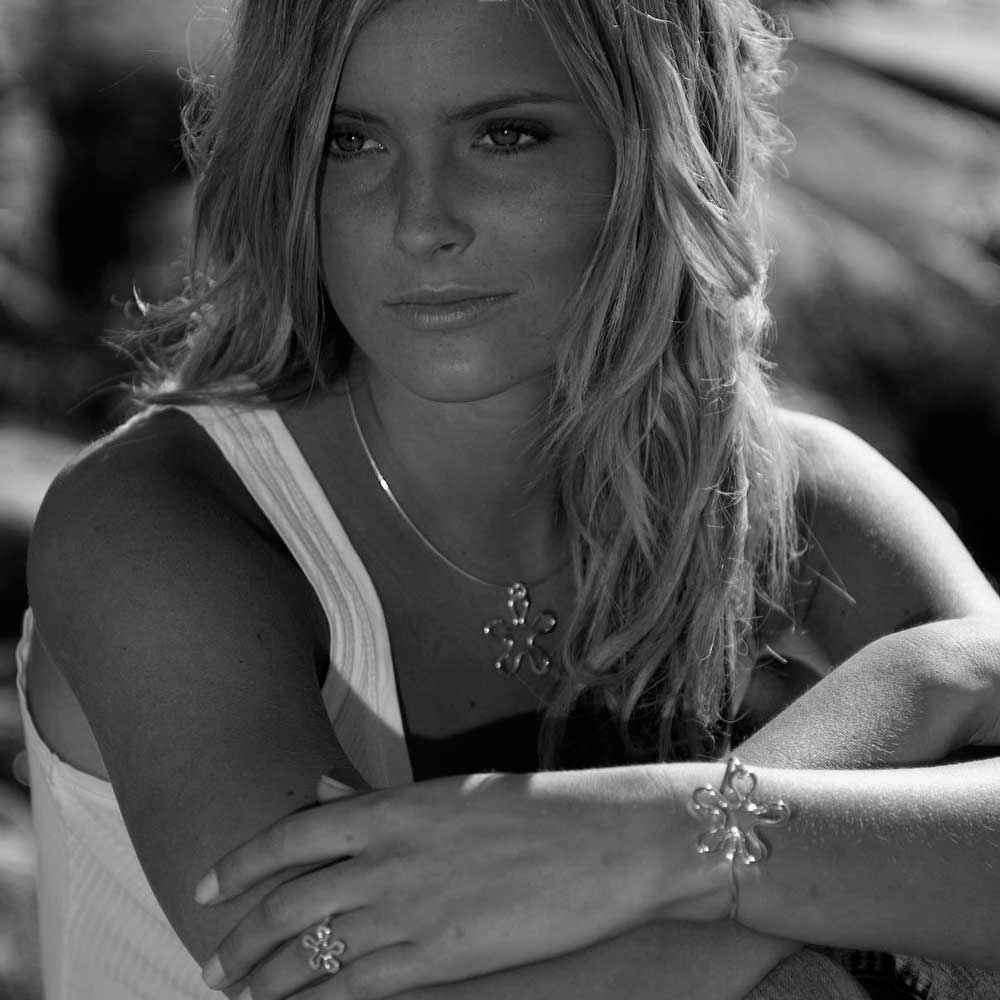 Model wears BLOMMAN flower pendant necklace and matching bracelet in sterling silver.