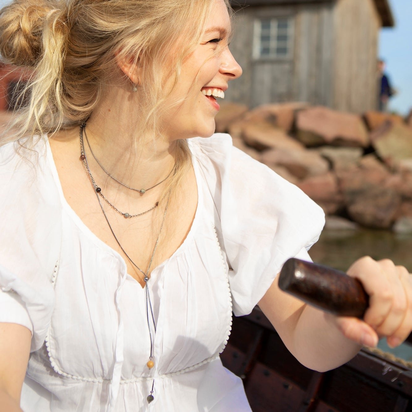 Kvinna poserar utomhus iklädd STRAND Pärla fest halsband med flera små stenar på tunna kedjor