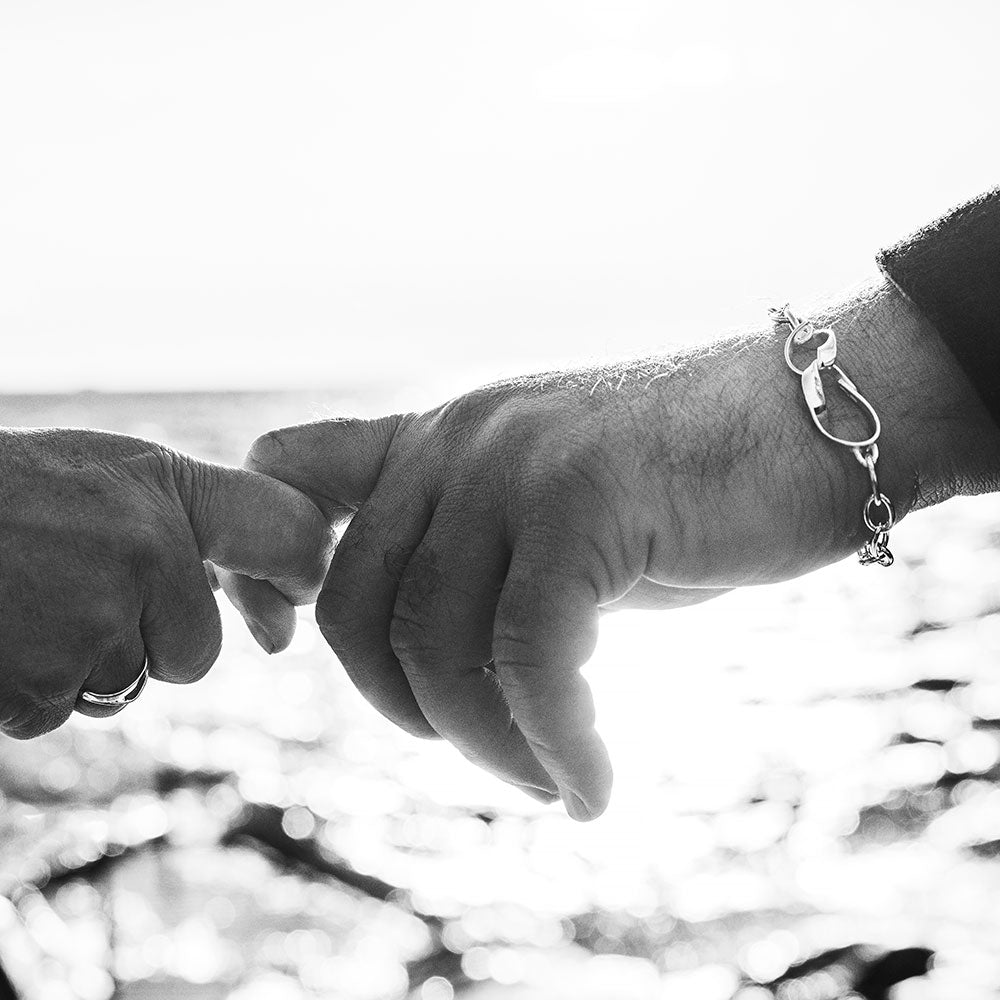 STORMSKÄRS MAJA Nät armband i silver på handled vid havet i svartvit bild