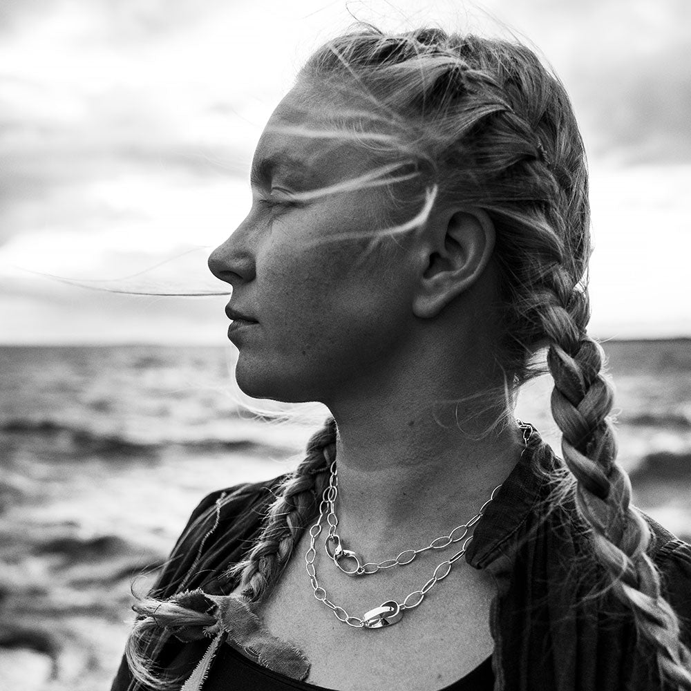 Profile of a woman wearing a 90 cm sterling silver STORMSKÄRS MAJA NÄT necklace with layered chains and a large central clasp.