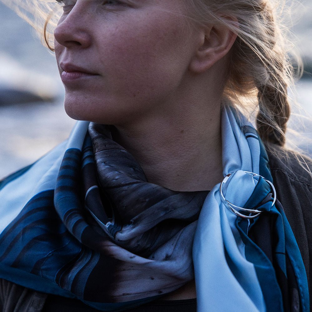 Silver scarfring worn on a blue scarf around the neck