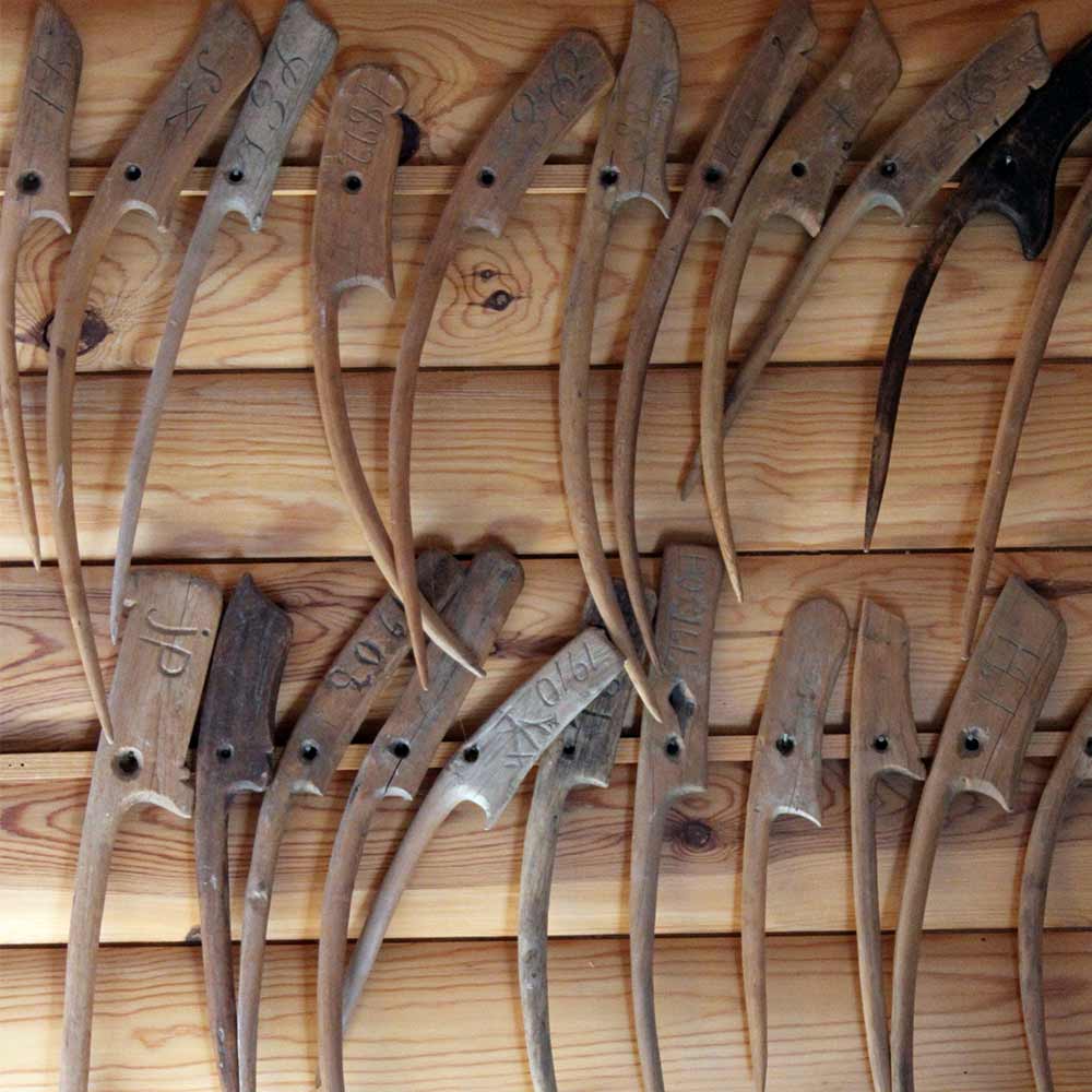 Row of wooden nätsticka fishing net needles with engraved markings hanging on a wooden rack