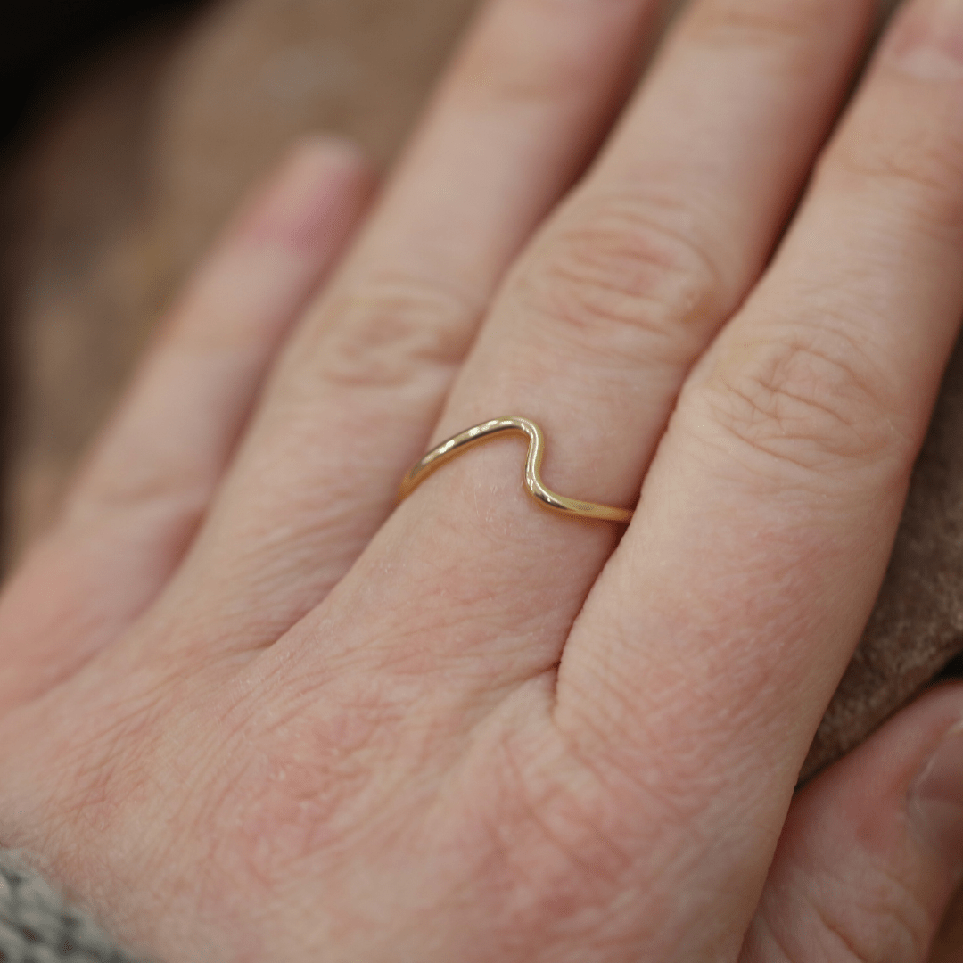 VÅGEN 18K gold ring with a gentle wave shape worn on a finger