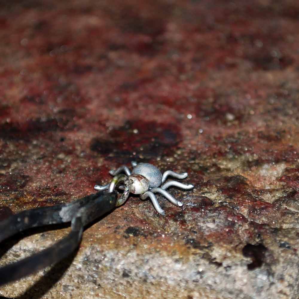 Närbild av spindelhänge i antikbehandlat silver med ögla för kedja