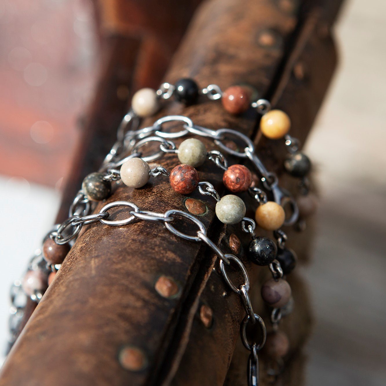 Armband kollektion med färgglada pärlor och metallringar draperade över en rostig metallstav.