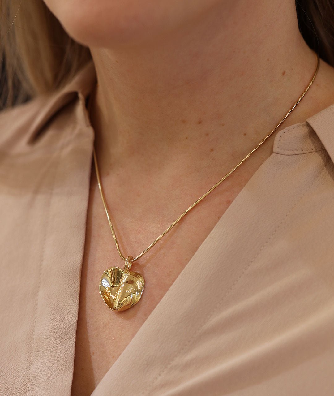 Two tone gold heart pendant on a slim chain worn by a model