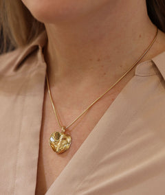 Two tone gold heart pendant on a slim chain worn by a model