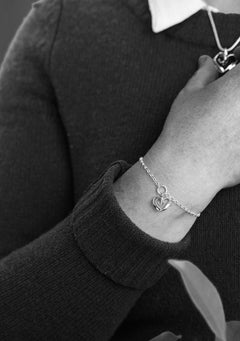 Närbild av STORMSKÄRS MAJA HJÄRTA armband med hjärtberlock runt handleden mot en mörk tröja