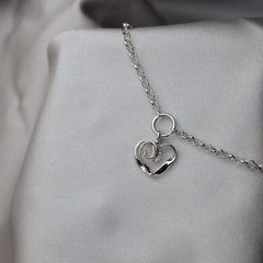 Närbild av silver armband med små ringformade länkar mot ljus tyg