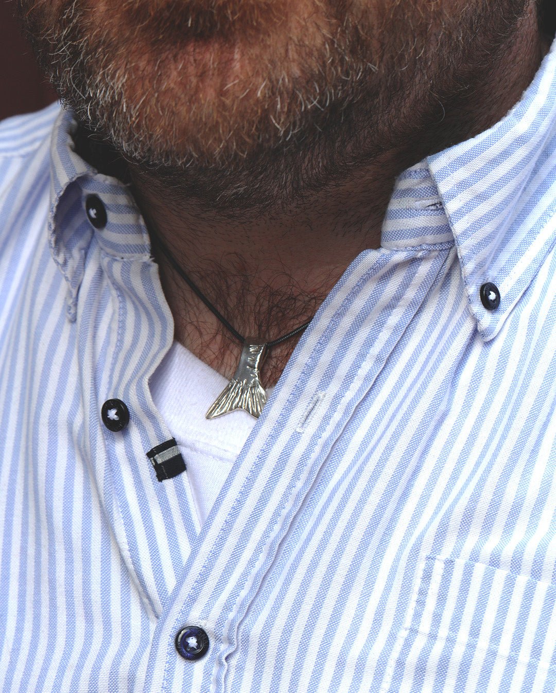 Man bär FENA halsband med silverfärgad stjärtfena på svart snöre