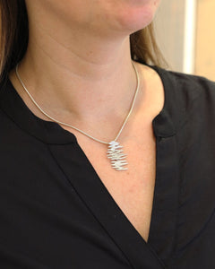 Close-up of the ALANDICA pendant on a silver chain worn at the neck