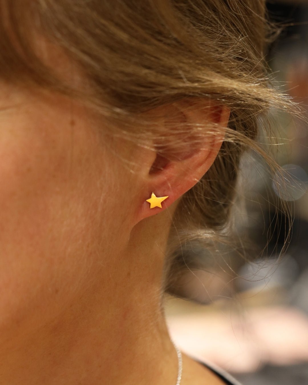 18K gold star stud earring worn on the earlobe