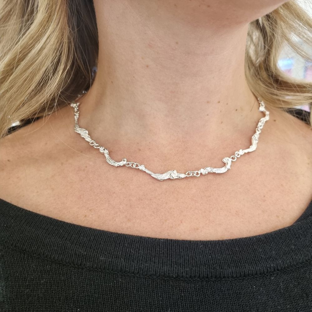 HAVET collier in 925 sterling silver resting on a model’s neck with a wavy textured chain inspired by stormy seas