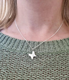 Model wearing FJÄRIL LILLA butterfly pendant on a silver chain.