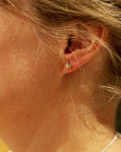 Small 18K gold star stud earring on the earlobe