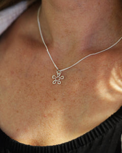 Model wearing BLOMMAN XS necklace with a silver flower pendant resting at the collarbone