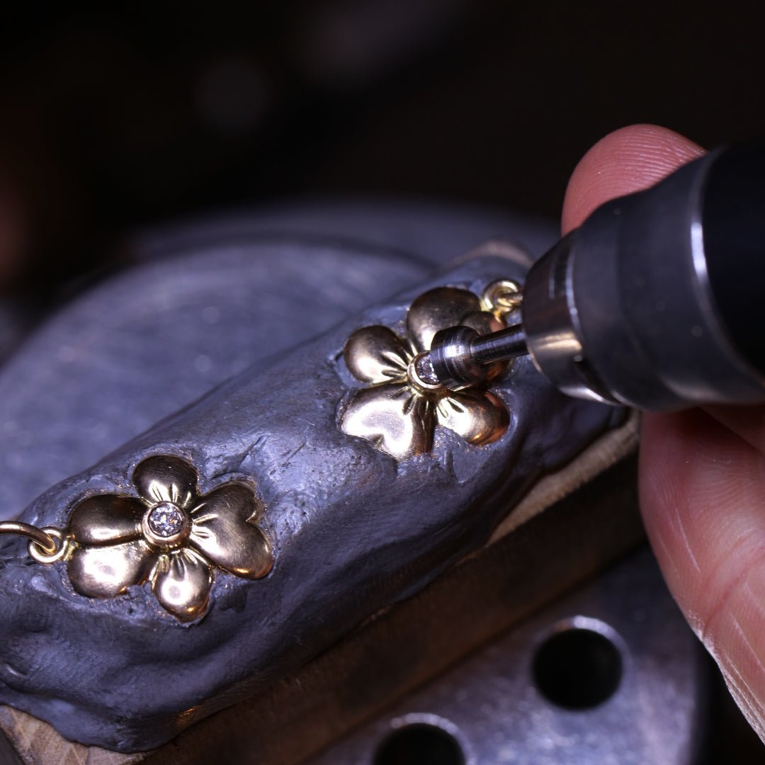 Närbild på VIOL S 18K halsband med blomformade kronblad och diamant i mitten