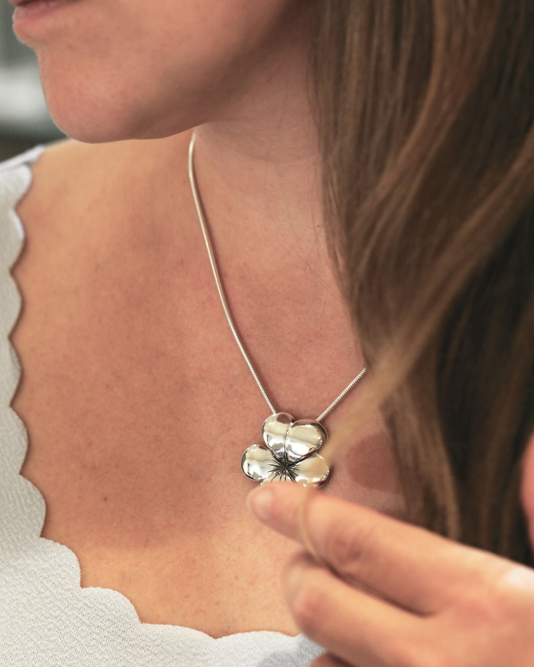 Närbild av kvinna som bär VIOL halsband med blomformigt hänge i silver