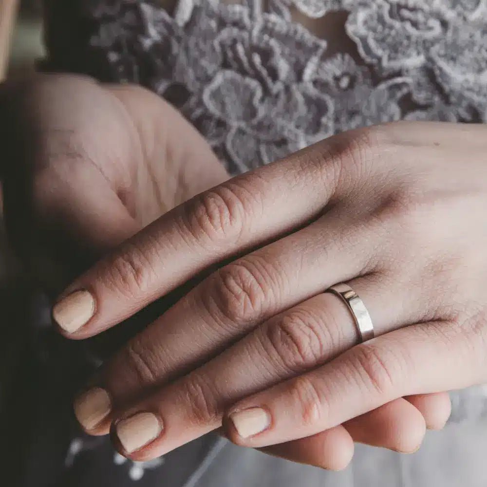 Hand visar en enkel slät rektangulär ring i 18K guld på fingret