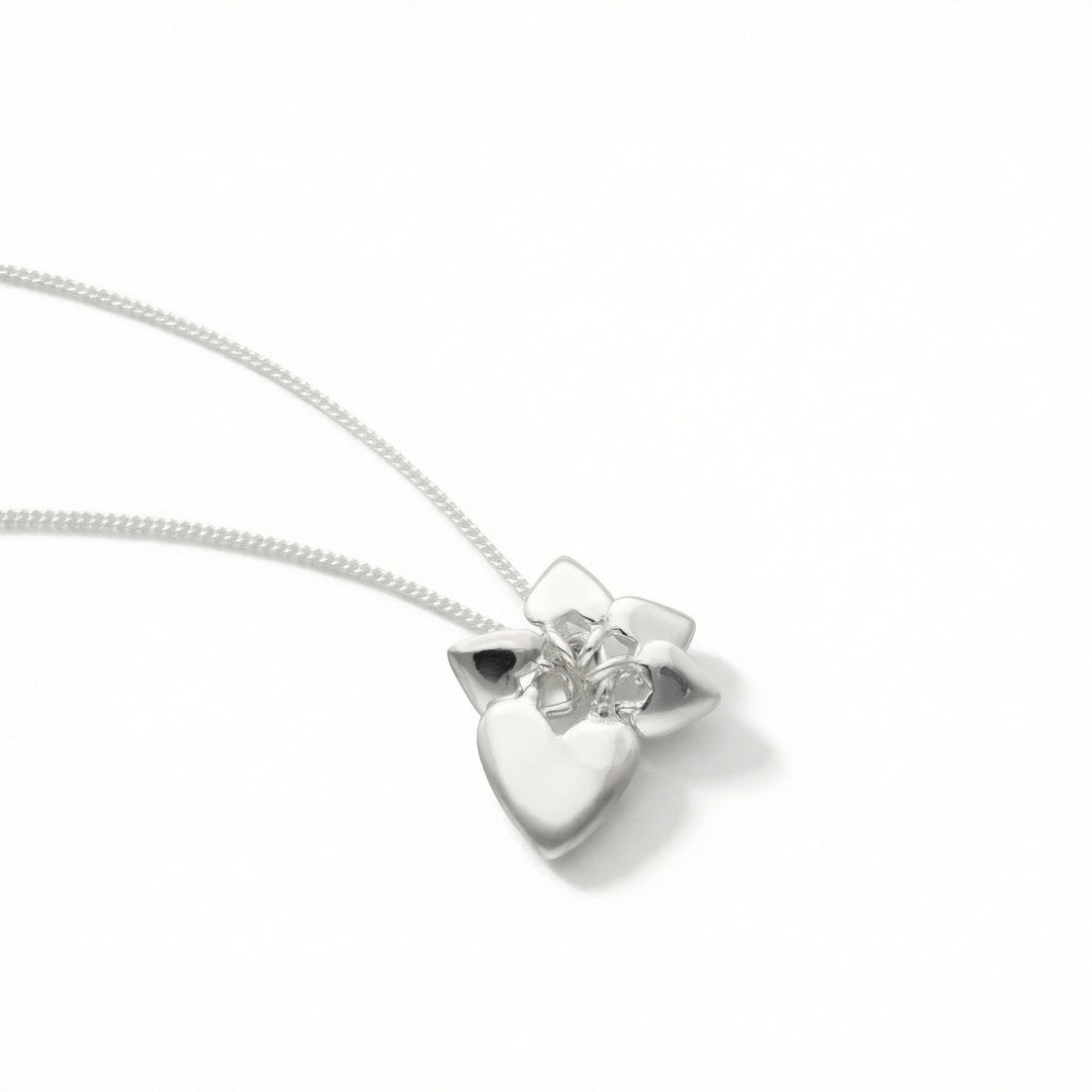 Close up of a silver heart and flower pendant on a chain
