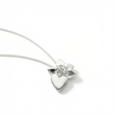 Close up of a silver heart and flower pendant on a chain