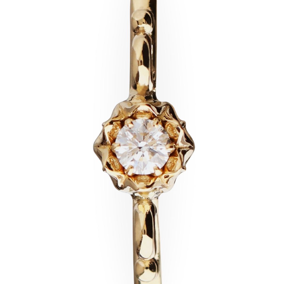 Close up of an 18K gold Lily of Love ring with a diamond set in a flower-shaped prong setting.